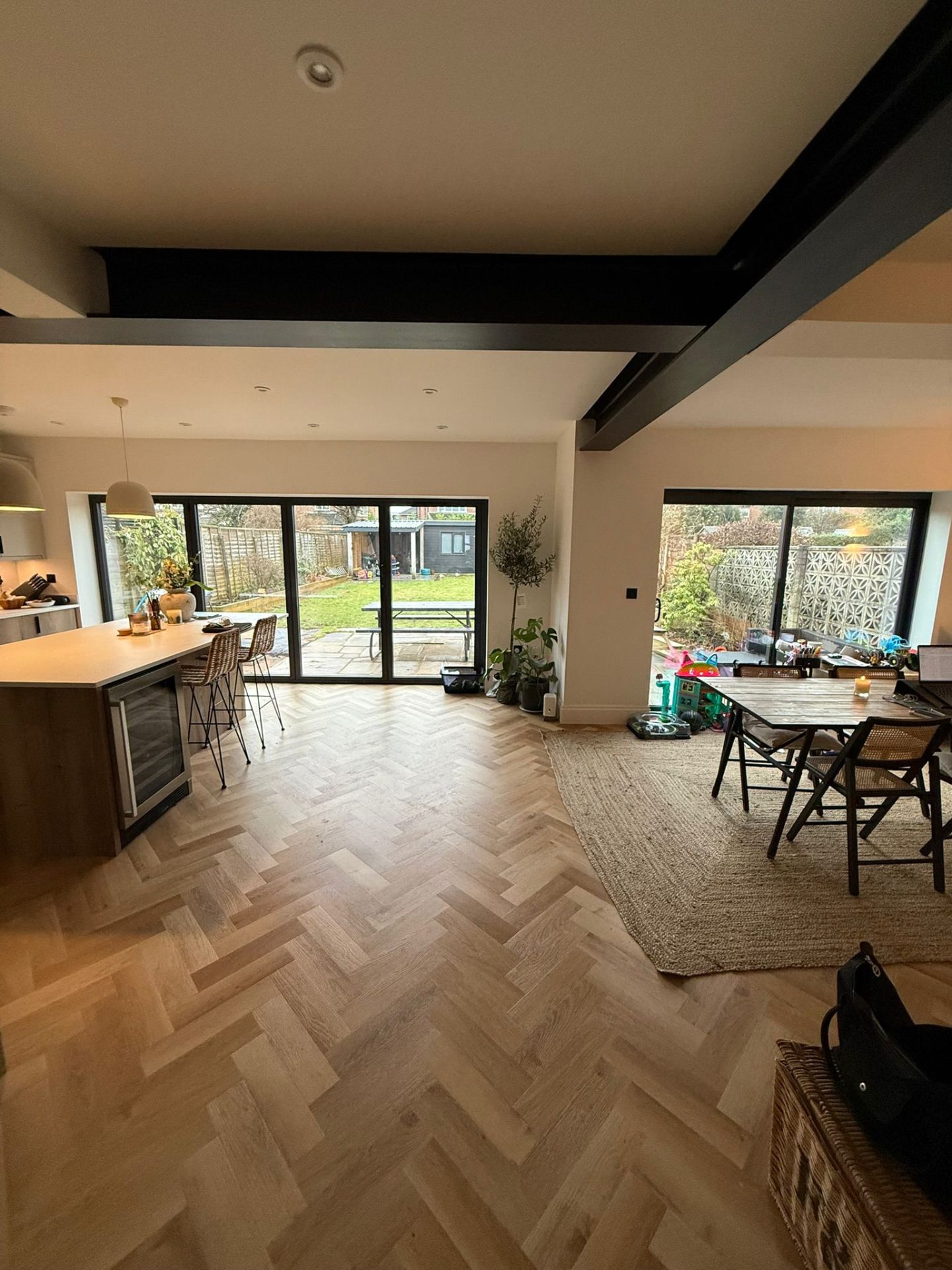 Open-plan rear extension with exposed steel beams, bifold doors and herringbone flooring